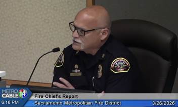 A person in uniform sitting at a desk with a microphone
AI-generated content may be incorrect.